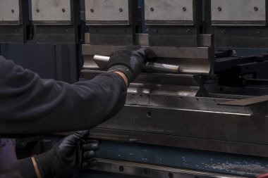 Düz metal levha için hidrolik fren ya da bükme makinesi. Bükme makinesindeki işçi bükme levhası metali.