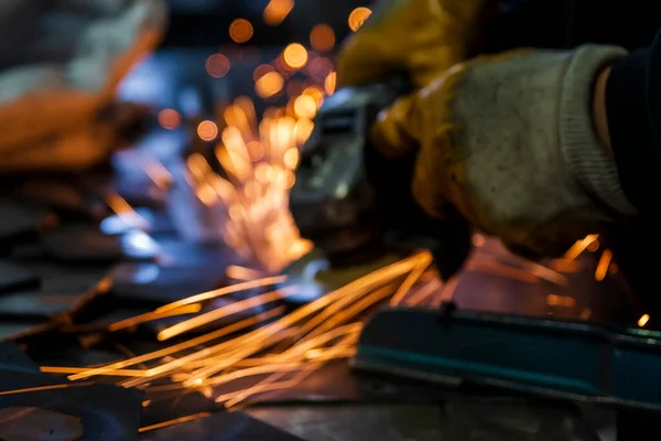 Grinding metal plates with electric wheel in factory. Sparks from the grinding wheel. Selective focus grinding machine and metal plates. Motion blur sparks