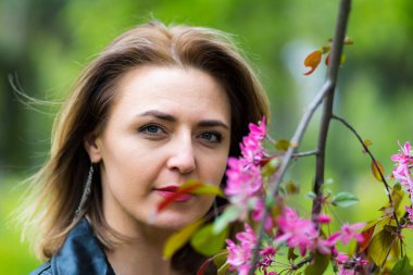 Çiçek açan ağaçlarda parktaki bir kadının portresi..