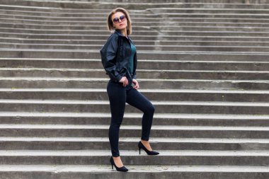 Şehir ortamında, şehir merdivenlerinde siyah elbiseli bir kadının portresi. Özgür ve bağımsız kadın kavramı