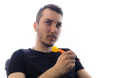 Genç ve yakışıklı bir adam hafif bir arka planda ciddi ve etkileyici bir şekilde gözlerinin içine bakar.