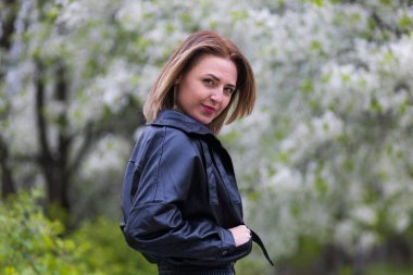 Otuz yaşından büyük mutlu bir kadının portresi çiçek açan ağaçların bulanık arka planında. Metin için kopyalama alanı