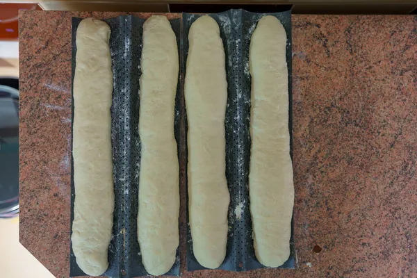 Dough in the kitchen. French baguettes on a baking sheet. Homemade bread baking. Background with selective focus and copy space for text