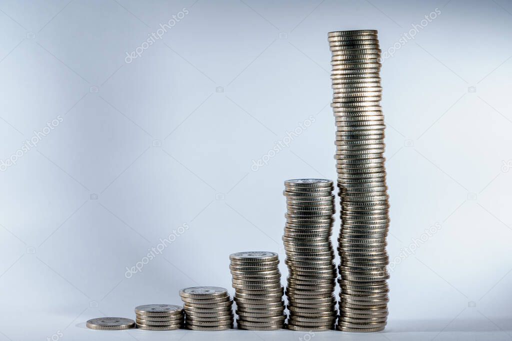 Stacks of coins in a growing progression. Background with copy space for text or inscriptions. Business economic development concept