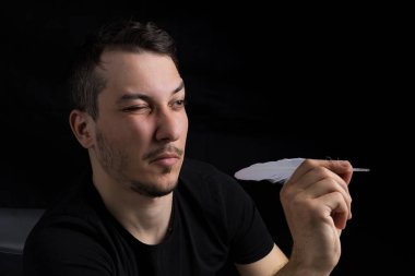 Kaz tüyü giymiş siyah giysili genç yakışıklı bir adam, siyah arka planda gizli bir dart metaforu. Hedef belirleme kavramı