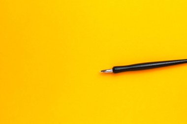 Metin veya yazıtlar için kopyalama alanı olan sarı bir arkaplan üzerindeki kalem.