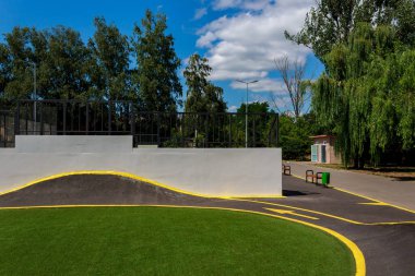 Şehir parkında slaytlı bisiklet yolu elemanı. Bisikletler ve kaykaylar için patika. Patenler için sıra dışı bir yol. Kentsel bir çevrede kaykay parkı. Arkaplan