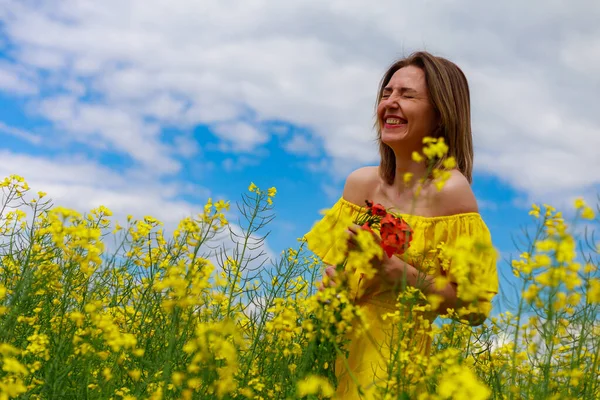 菜の花畑の明るい黄色の背景の雷の上に黄色のドレスの若いかなりの女性 インスピレーションコンセプト — ストック写真