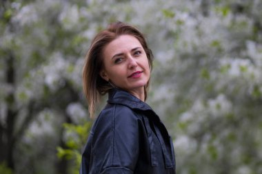 Otuz yaşından büyük mutlu bir kadının portresi çiçek açan ağaçların bulanık arka planında. Metin için kopyalama alanı