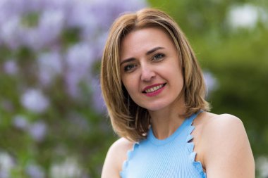 Otuz yaşından büyük mutlu bir kadının portresi çiçek açan ağaçların bulanık arka planında. Metin için kopyalama alanı