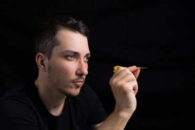 Siyah elbiseli, siyah arka planda kırmızı dartlı yakışıklı bir adam. Hedef belirleme kavramı