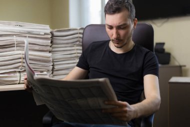 Bulanık ofis geçmişinde gazete okuyan genç bir adam..