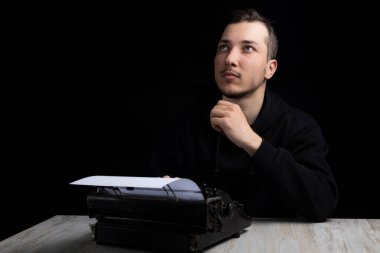 Siyah kapüşonlu genç yakışıklı daktiloyla siyah arka planda sade bir şekilde yukarı bakıyor.