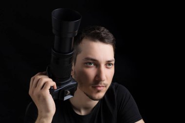 Siyah elbiseli, siyah elbiseli genç adam düz görünüyor, siyah arka planda, sade bir anahtarla. Metin için kopyalama alanı