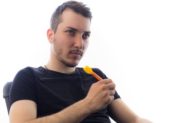 Genç ve yakışıklı bir adam hafif bir arka planda ciddi ve etkileyici bir şekilde gözlerinin içine bakar.