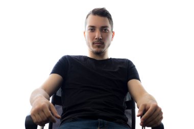 Genç ve yakışıklı bir adam hafif bir arka planda ciddi ve etkileyici bir şekilde gözlerinin içine bakar.