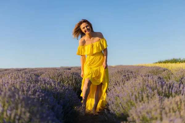 黄色のドレスのリラックスした美しいとかなり若い女性と日没のラベンダー畑で散歩を楽しんで トーン — ストック写真