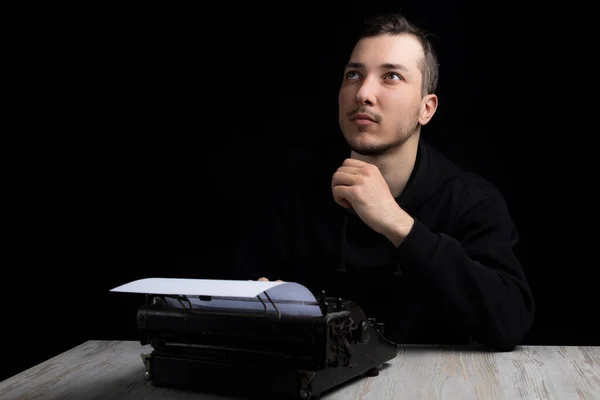 Молодой Красивый Мужчина Черной Толстовке Пишущей Машинкой Мечтательно Смотрящий Черном — стоковое фото