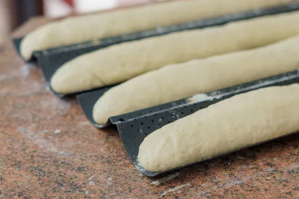 Dough in the kitchen. French baguettes on a baking sheet. Homemade bread baking. Background with selective focus and copy space for text