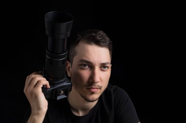 Siyah elbiseli, siyah elbiseli genç adam düz görünüyor, siyah arka planda, sade bir anahtarla. Metin için kopyalama alanı