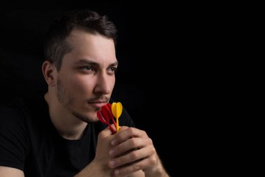 Siyah elbiseli, elinde dartlarla siyah arka planda, sade bir anahtarla dolaşan yakışıklı bir genç. Hedefe hazır olma kavramı