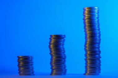 Renkli steampunk loş ışıklarıyla aydınlatılan artan ilerlemedeki bozuk para yığınları. Metin veya yazıtlar için kopyalama alanı olan bir arkaplan. Ticari ekonomik kalkınma kavramı.