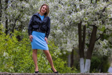 Otuz yaşından büyük mutlu bir kadının portresi çiçek açan ağaçların bulanık arka planında. Metin için kopyalama alanı