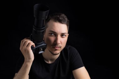 Siyah elbiseli, siyah elbiseli genç adam düz görünüyor, siyah arka planda, sade bir anahtarla. Metin için kopyalama alanı