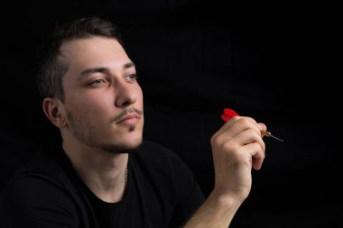 Siyah elbiseli, siyah arka planda kırmızı dartlı yakışıklı bir adam. Hedef belirleme kavramı
