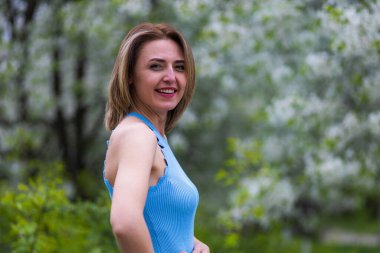 Otuz yaşından büyük mutlu bir kadının portresi çiçek açan ağaçların bulanık arka planında. Metin için kopyalama alanı