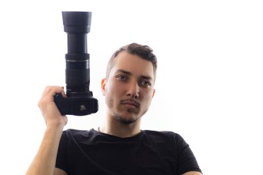 Kameralı yakışıklı bir genç adam, gözlere özen gösteriyor. Beyaz arkaplanda bir portre.