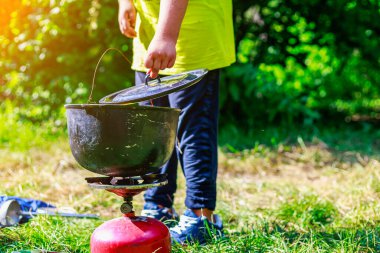 A cauldron or pot of food on a gas burner in the wild. Hiking food at the tourist camp. Background with copy space for text