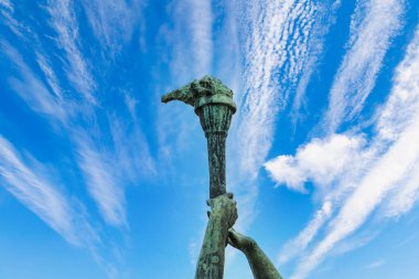 An element of a stone monument a torch in hand on the backdrop of a beautiful sky. A symbol of light and progress. Background with copy space for text or inscriptions.