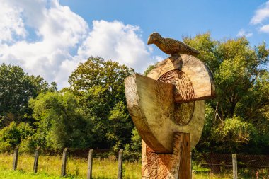 Kuşla birlikte soyut, rustik sütunlar oyulmuş. Odun oyma dünyadaki farklı insanların kültüründe popüler bir hobidir..