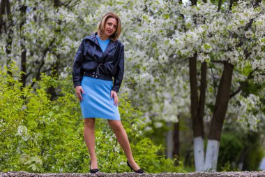 Otuz yaşından büyük mutlu bir kadının portresi çiçek açan ağaçların bulanık arka planında. Metin için kopyalama alanı