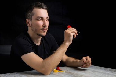 Siyah elbiseli, siyah arka planda kırmızı dartlı yakışıklı bir adam. Hedef belirleme kavramı