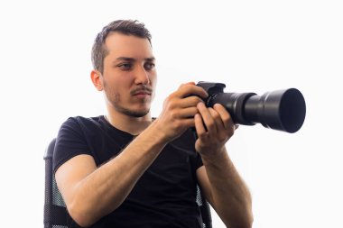 Kameralı yakışıklı bir genç adam, gözlere özen gösteriyor. Beyaz arkaplanda bir portre.