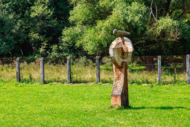 Kuşla birlikte soyut, rustik sütunlar oyulmuş. Odun oyma dünyadaki farklı insanların kültüründe popüler bir hobidir..