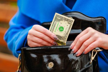 Bir kadının eli cüzdanından bir dolar çıkarır. Metin veya yazıtlar için kopyalama alanı olan arkaplan.