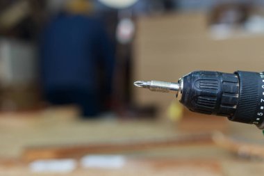 Bulanık bir atölyenin arka planında vida yerine vida parçası olan tornavida elementi. Metin veya yazı için kopyalama alanı olan arkaplan