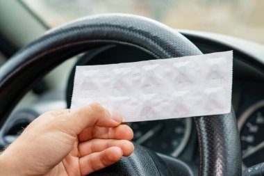 Arabadaki direksiyonun bulanık arka planında sürücünün elindeki haplar. Araba kullanırken tıbbi amaçlar için farmakolojik ilaç kullanımı. Seçici odak