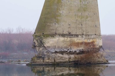 Rutubetli sisli havada nehrin üzerindeki uçurulan köprünün somut desteği. Savaşın sonuçları işte. Metin için kopyalama alanı olan arkaplan