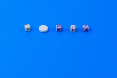 VOMIT metni küpten yapılmış. O harfi yerine puanı olan beyaz bir ilaç. Klasik geleneksel mavi arkaplan.