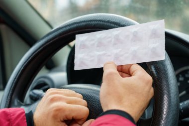 Arabadaki direksiyonun bulanık arka planında sürücünün elindeki haplar. Araba kullanırken tıbbi amaçlar için farmakolojik ilaç kullanımı. Seçici odak