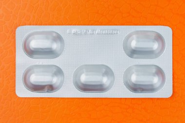 Kabarcık ya da beş tablet ya da hap paketi. Beş çalışma günü kavramı. Turuncu arka plan. Tıp ve farmakoloji.