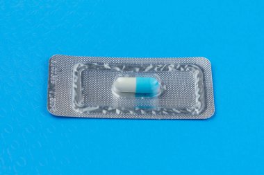 Çok önemli ve pahalı bir tablet ya da hap paketi. Klasik tıbbi mavi arka plan. Seçici odak ve kopyalama alanı.