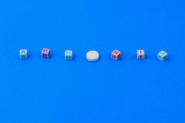 APHONIA metni küpten yapılmış, O harfi yerine puanı olan beyaz bir ilaç. Klasik geleneksel mavi arkaplan.