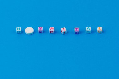 Metin HASTANESİ küpten yapılmış, O harfi yerine puanlı beyaz bir hap. Klasik geleneksel mavi arkaplan