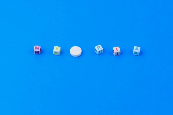 Myopiaテキストキューブで作られました 手紙Oの代わりにスコアを持つ白い医療用錠剤 古典的な青の背景 — ストック写真
