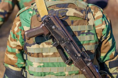 Bir askerin sırtında şarjörü olmayan otomatik bir tüfek. Seçici odaklı arkaplan ve metin için alanı kopyala